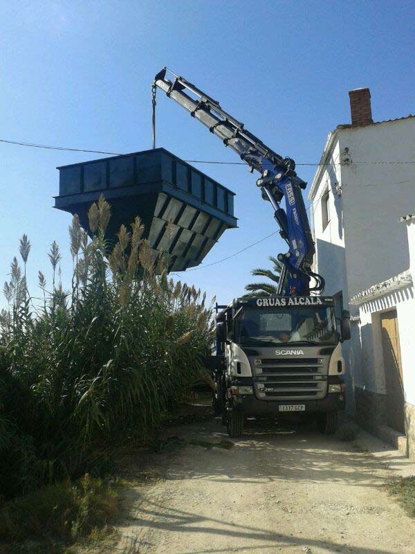 camión con grúa elevando estructura