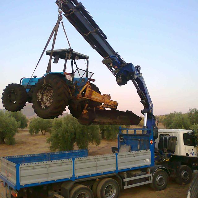 camión con grúa elevando tractor