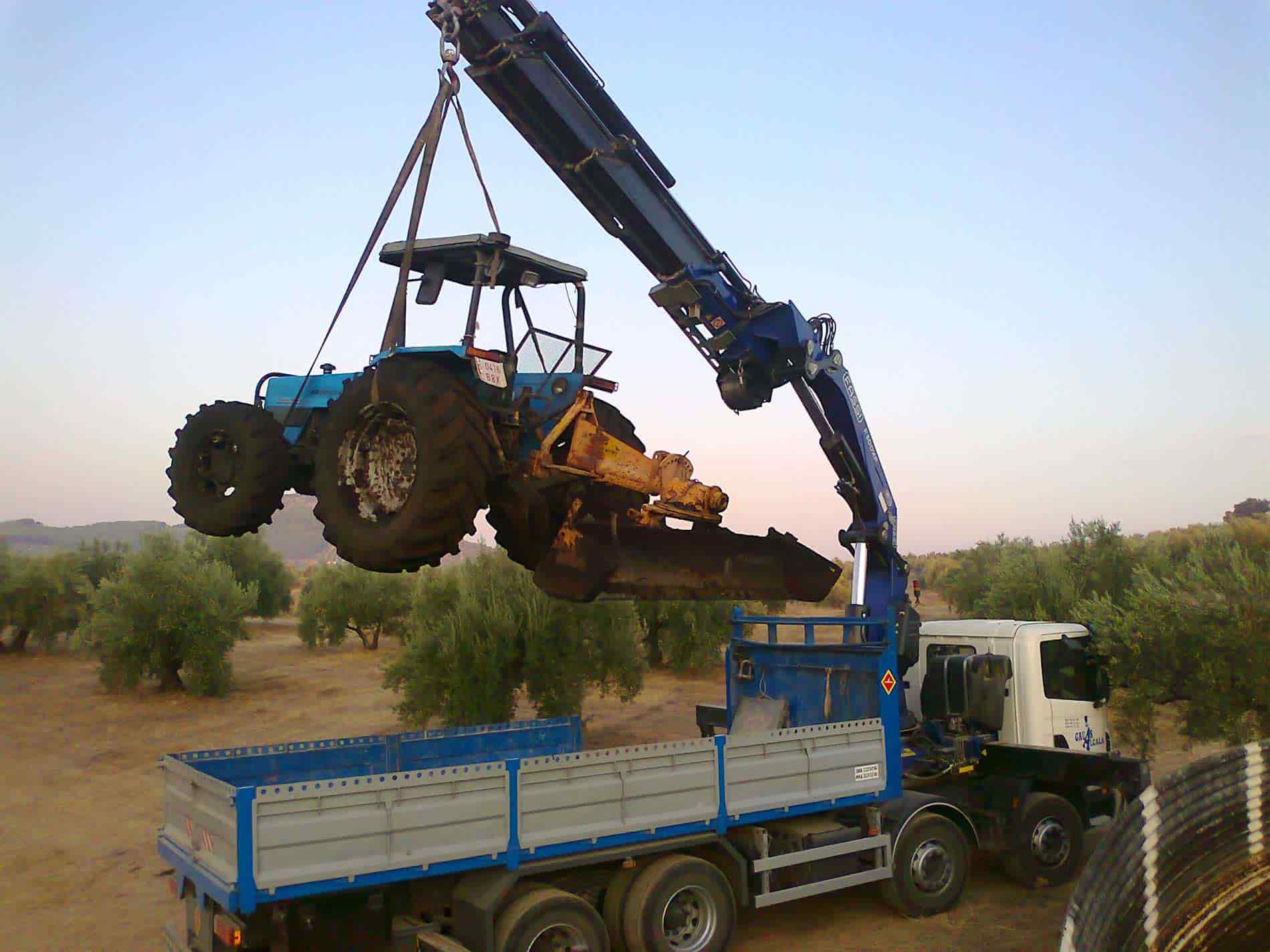 camión con grúa elevando tractor